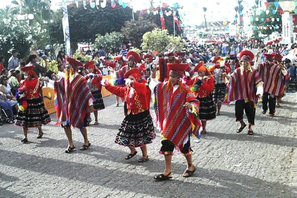 Jugendliche stellen auf einem Umzug den traditionellen Huayno-Tanz dar. 