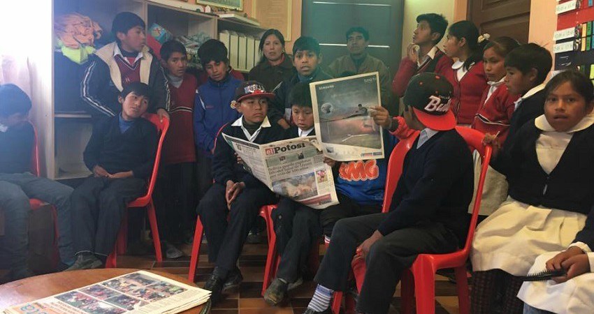 Kinderrechte in Bolivien: Treffen mit jungen Gewerkschaftlern in Potosí. Eine Gruppe Kinder sitzt auf Plastikstühlen und liest die Tageszeitung von Potosí.
