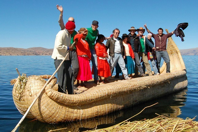 Eine Viventura Reisegruppe stehen mit Einheimischen in einem Schilfboot am Titicacasee.